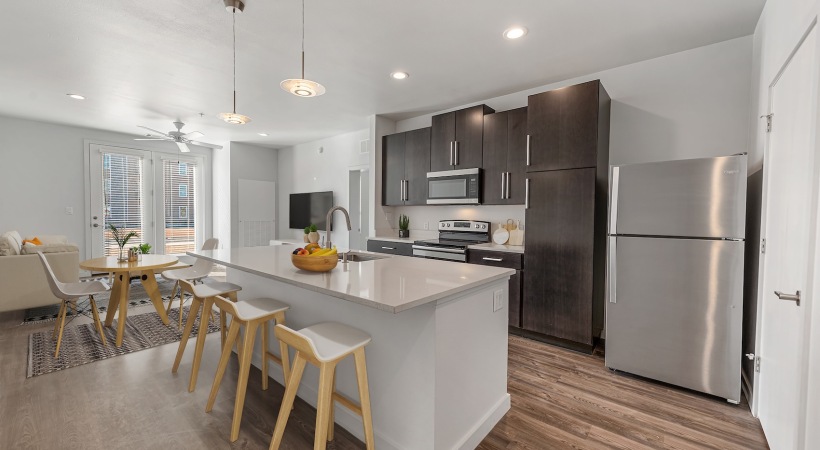 Model kitchen at our apartments for rent in Midland, TX, featuring wood grain floor paneling and stainless steel appliances.
